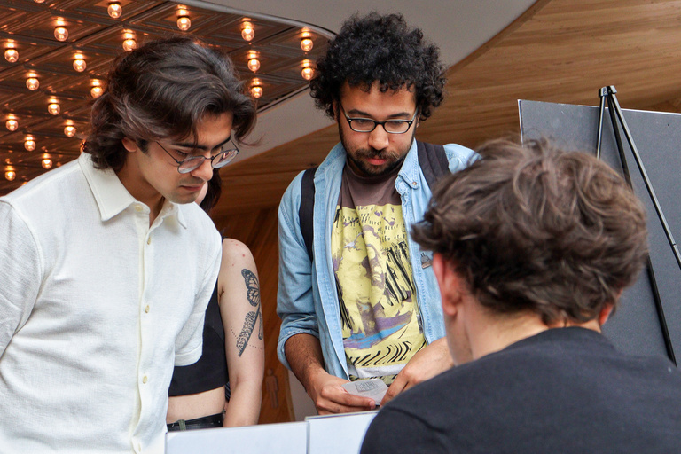 Two students stand at a table at the Iowa City Documentary Film Festival while a third sits behind it.