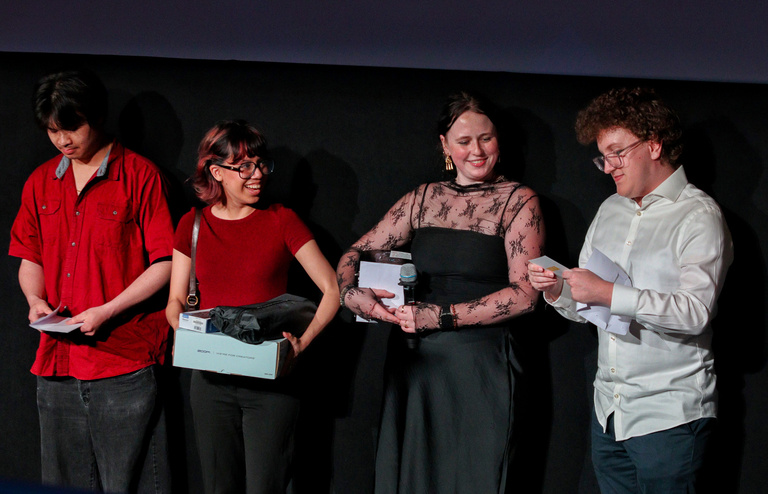 Four students against a black background announce prize winners at the Iowa City Documentary Film Festival.